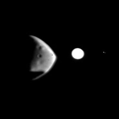 Black and white shot of Deimos, Mars' lopsided-shaped moon, with glowing Jupiter in the background