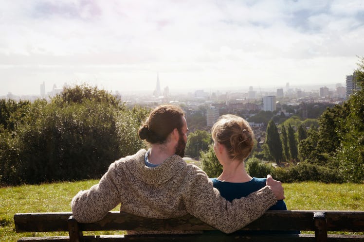 Couple sitting in an embrace on a rooftop looking at the sunset while swirls of light surround them.