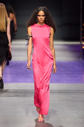 a model wears a pink dress on the versace runway 