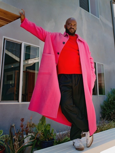 Selema Masekela wearing a pink wool coat, red top and sneakers.