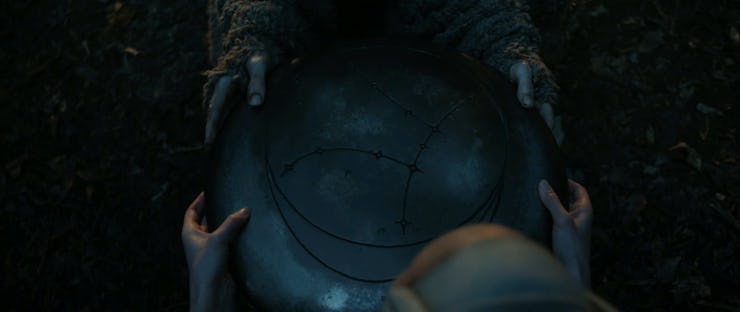 The Stranger (Daniel Weyman) holds a metal disc in the Season 1 finale of The Lord of the Rings: The...