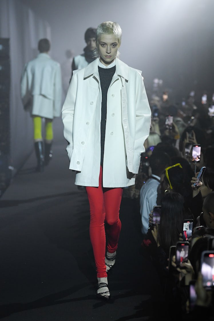 A model walking in a white blazer and red leggings at a Raf Simons spring 2023 runway