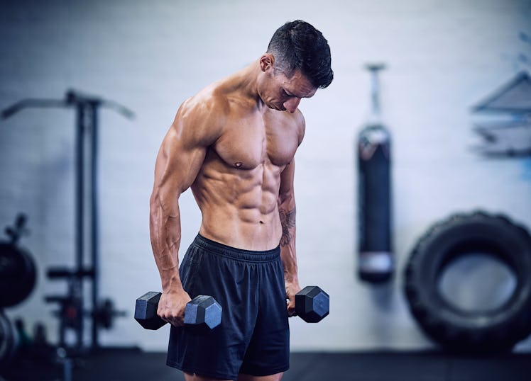 A fit, shirtless man with defined muscles holding dumbbells.