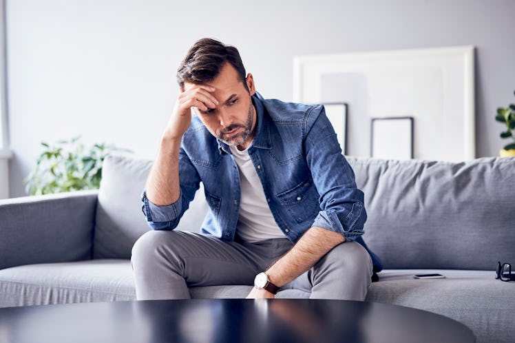 A man sitting on a couch and thinking how to let go of a grudge