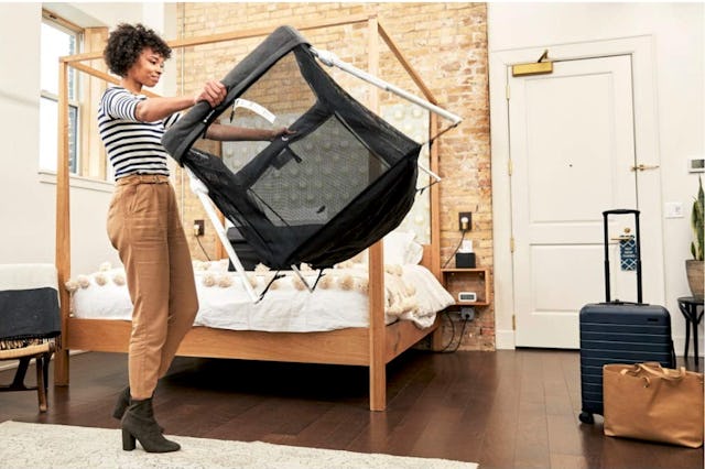 A mother moving a pack 'n play around her bedroom