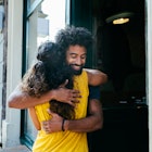 Male and female friends hugging outside of a restaurant