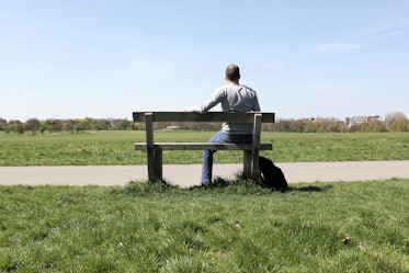 中年男人坐在公园的长椅上独自面对远离相机