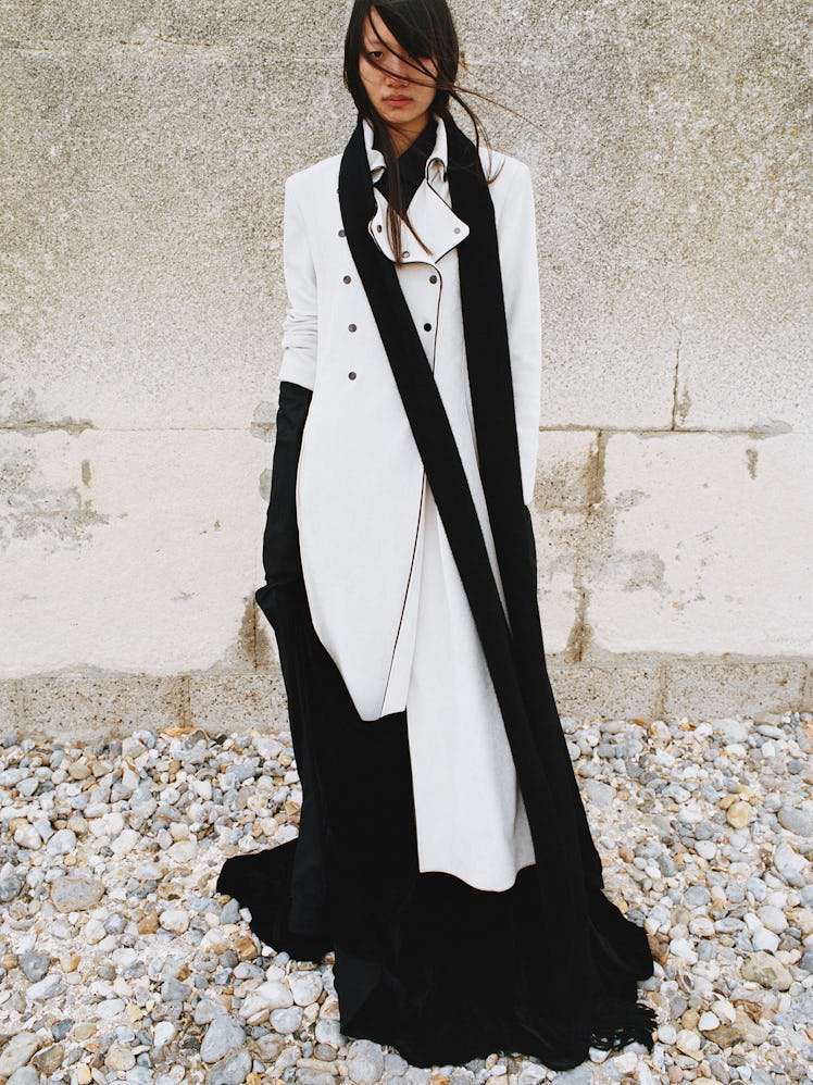 Luoyi wears a white coat, black dress and scarf.