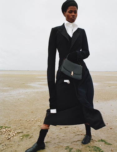 Victoria Fawole wears a black coat, bag, hat and shoes.