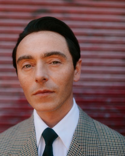 A portrait of David Dawson wearing a plaid suit and black tie