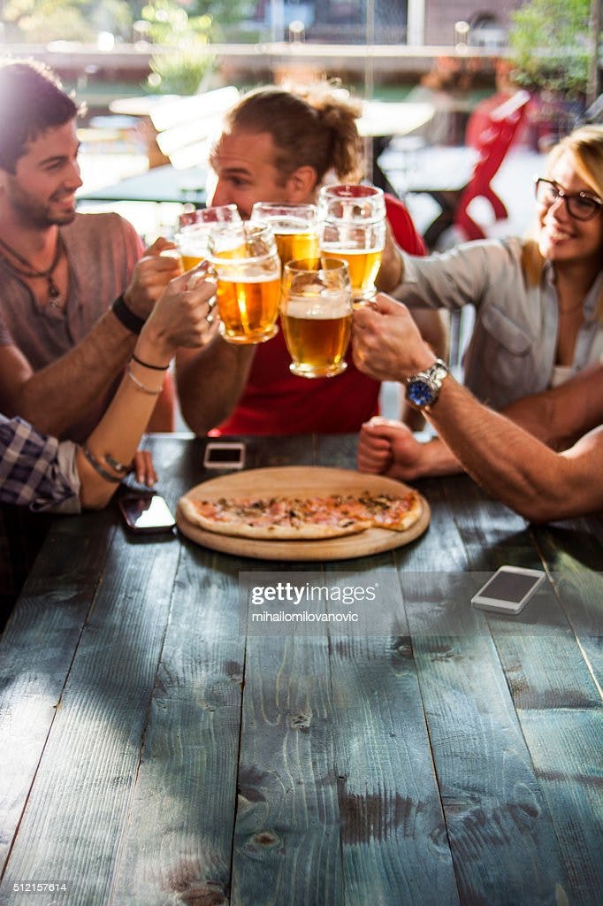 Group of friends having a beer while eating pizza