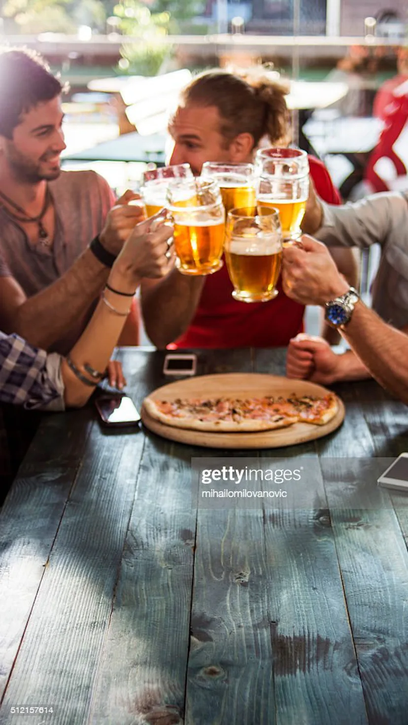 Group of friends having a beer while eating pizza