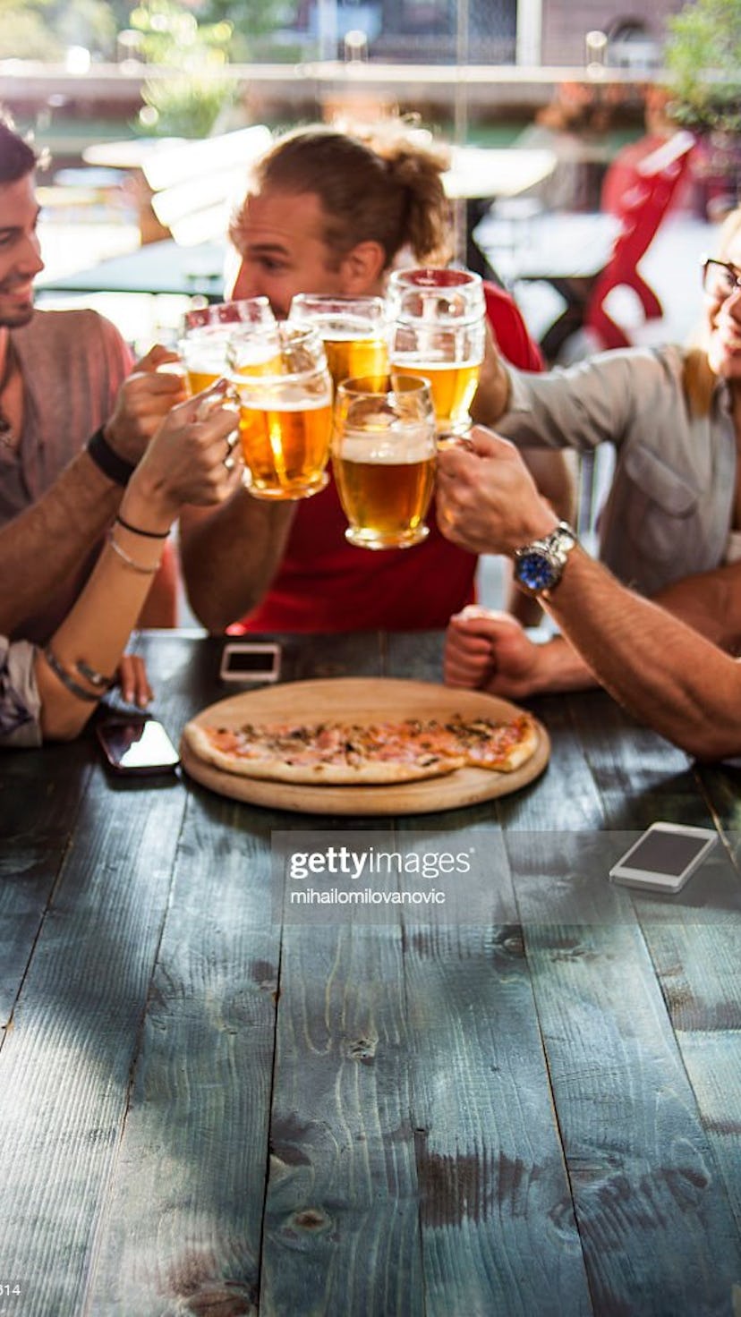 Group of friends having a beer while eating pizza