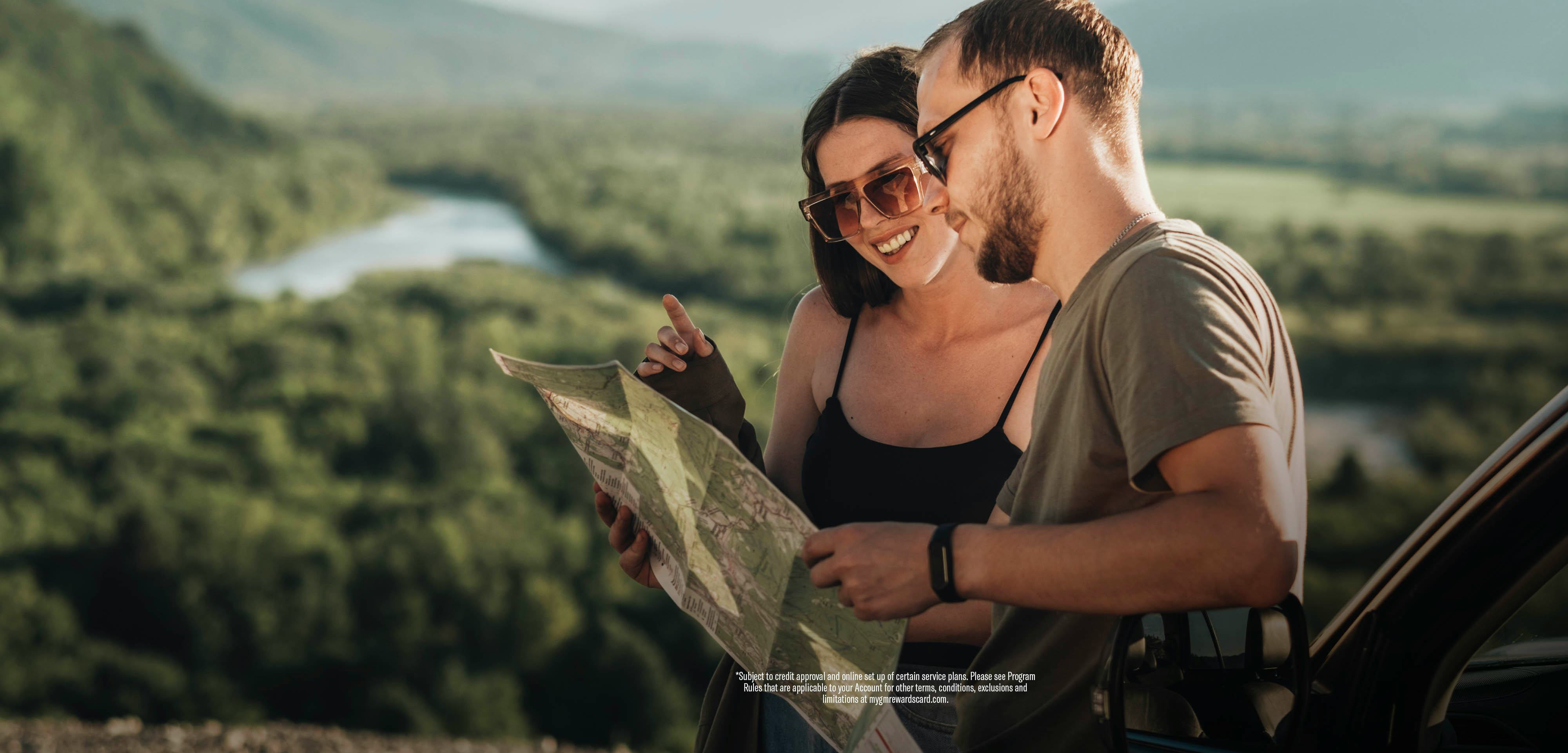 Young couple looking at a map, and planning their trip, with smiles on their faces.