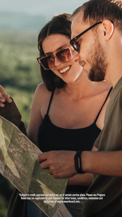 Young couple looking at a map, and planning their trip, with smiles on their faces.
