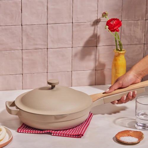 A hand holding the Always Pan from Our Place's Fall 2022 sale on a kitchen counter 