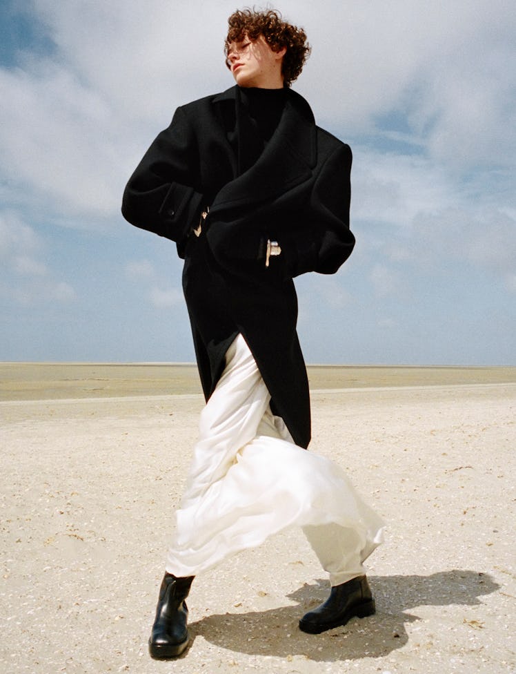 Greta Bultmann wears a Saint Laurent by Anthony Vaccarello coat, dress, and bracelets; Tod’s boots; ...