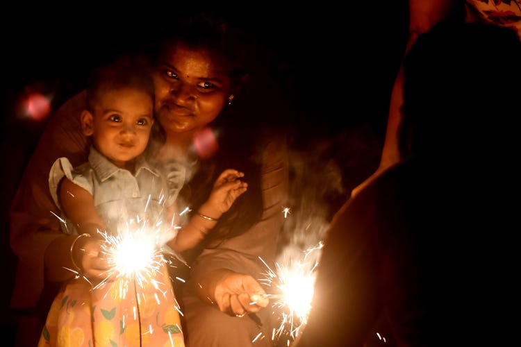 A mother and her daughter light a sparkler during Diwali in Chennai, India.