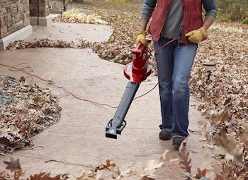 person using leaf vacuum along pathway