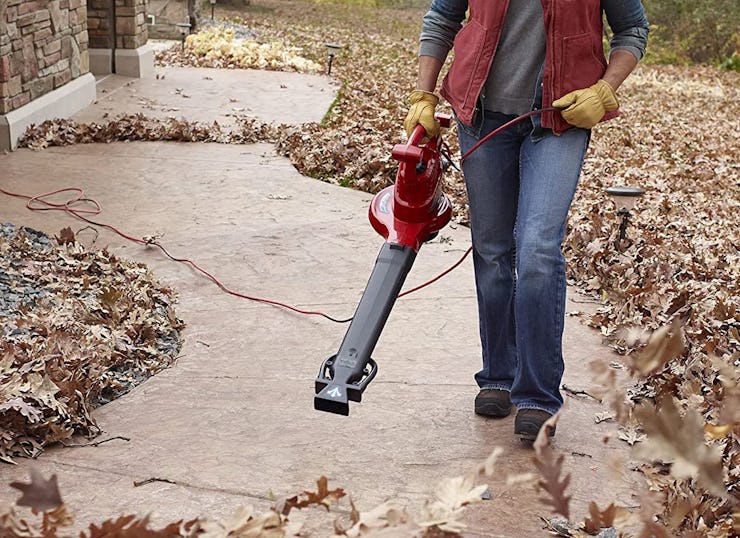 person using leaf vacuum along pathway