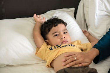 A parent's hand on the belly of a toddler with a tummy ache.