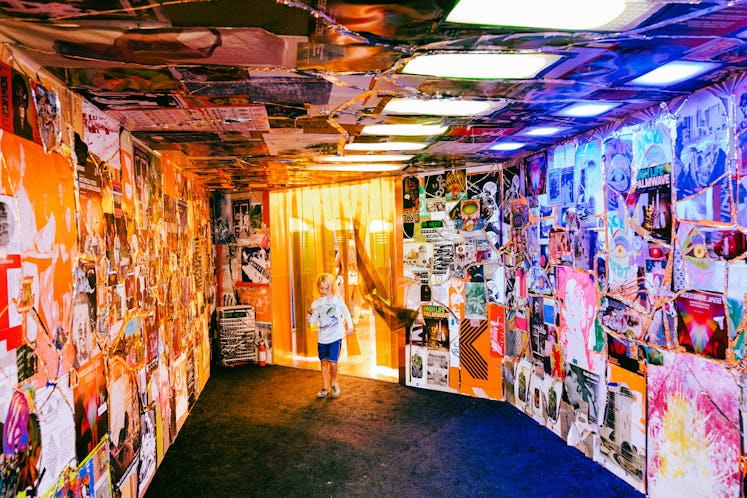 a kid running through a multicolored hallway with pictures pasted on the wall