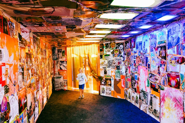 a kid running through a multicolored hallway with pictures pasted on the wall