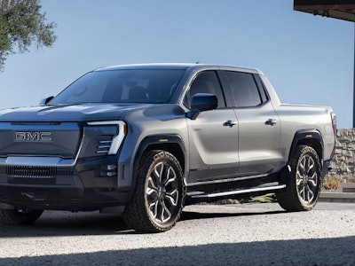 A new pickup truck Sierra EV Denali parked in front of a house