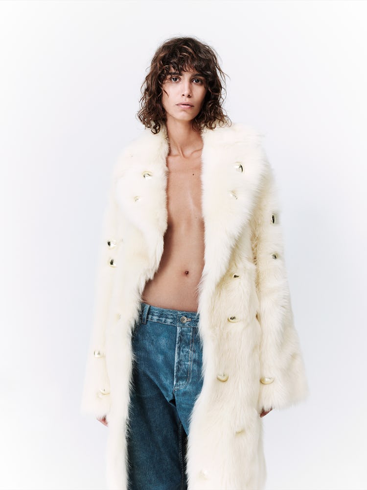 Model wears a white fur coat with denim jeans.