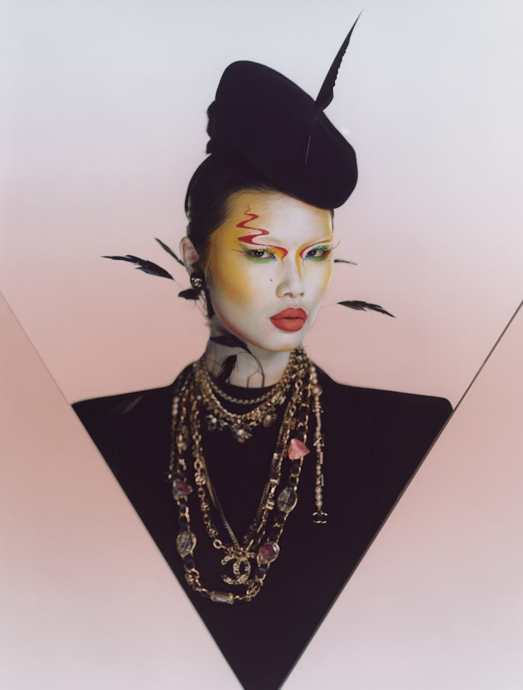 Kayako Higuchi wears a Prada dress; Emily-London hat; Chanel earrings, necklaces, and belts (worn as...