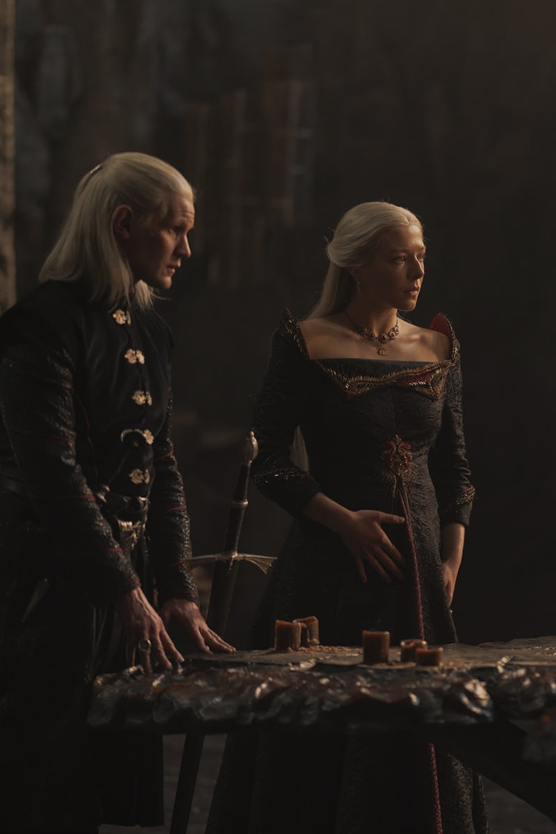 Rhaenyra Targaryen and  Daemon Targaryen standing next to each other at a large table