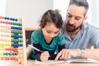 一位父亲用算盘帮助他的孩子做数学作业。