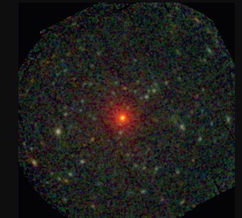 Color image of a red-orange star at the center of a grainy green and black field