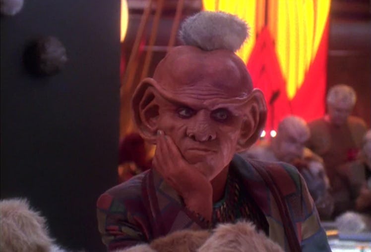 A still image of a disgruntled Ferengi covered in Tribbles. 