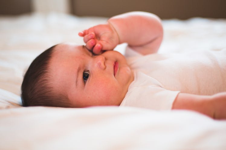 A baby rubbing one of their eyes.