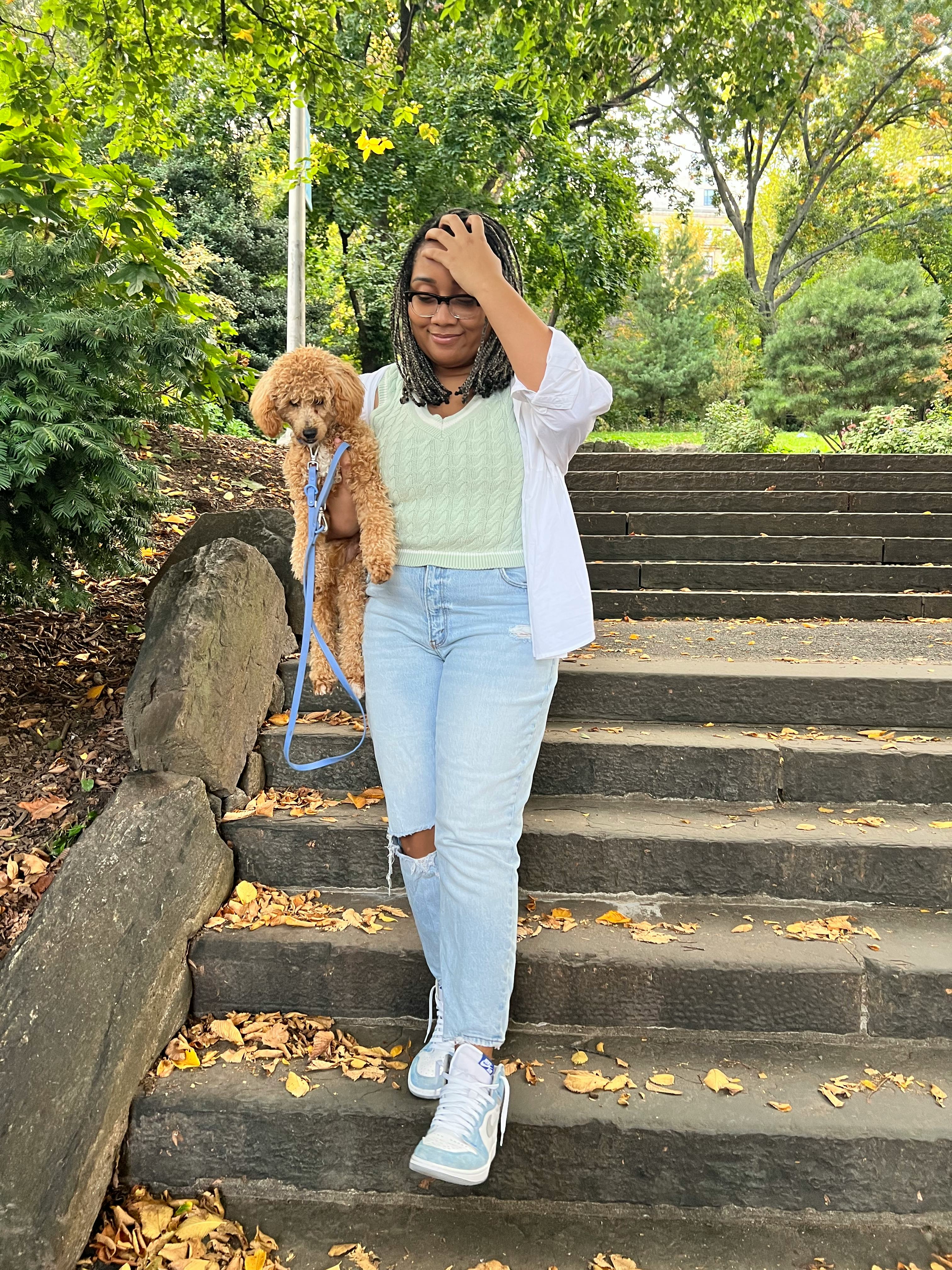 A mid-size woman walking down stairs in a green sweater vest and jeans by Abercrombie and carrying a&hellip;