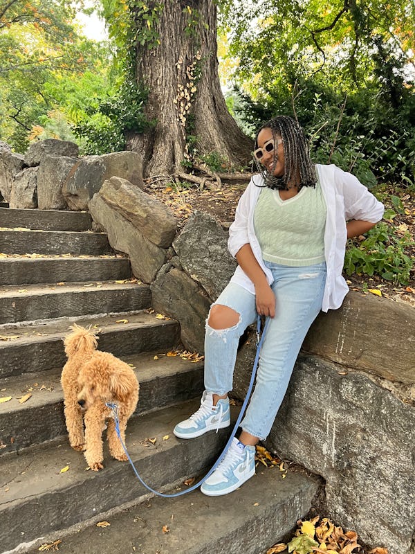 A mid-size woman standing on stairs in a green sweater vest and jeans by Abercrombie