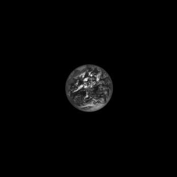 A black and white image of Earth. The planet appears small in this image, taking up about one-sixtee...