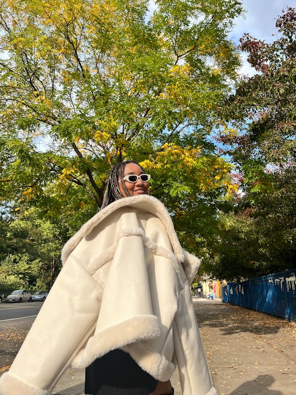 A mid-size woman posing in a white shearling jacket by Abercrombie