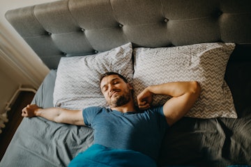 A man stretching in bed in the morning.