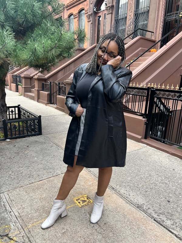 A mid-size woman posing in a black leather coat and a black mini skirt by Abercrombie