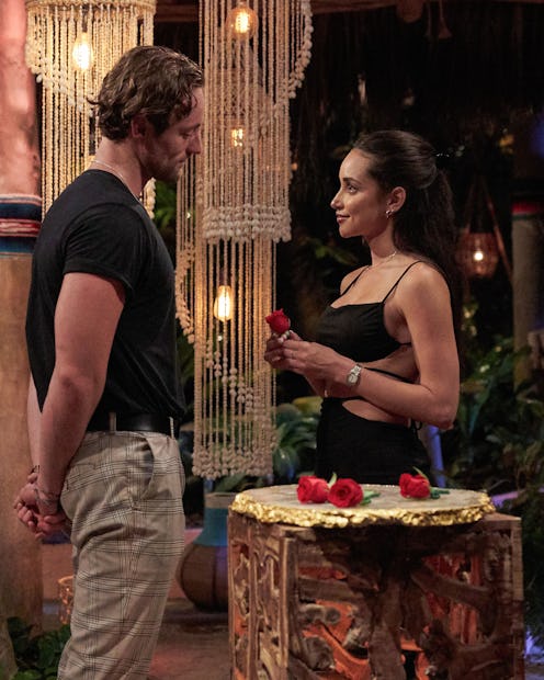 In a strappy black dress, Victoria Fuller holding a rose while talking eye-to-eye with Johnny DePhil...