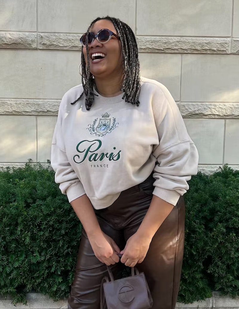 A mid-size woman in a white Abercrombie sweater with "Paris" embroidered on it 