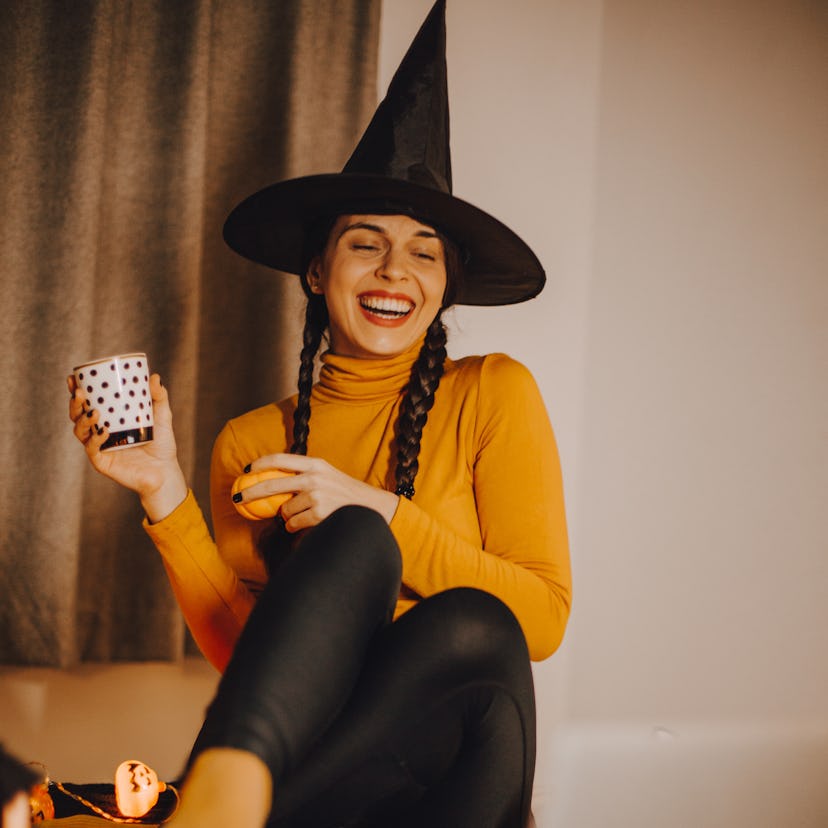 Young woman wearing a witch hat after she heard the last-minute Halloween 2022 costume for her zodia...