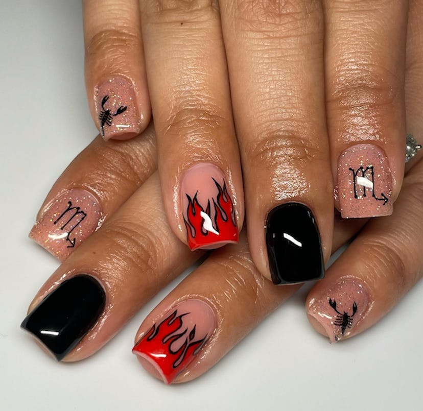 A Scorpio nail design with red flames and black accents.