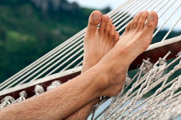 Close up of a man's sandy feet on a hammock.