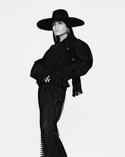 A black and white portrait of Yuna wearing a black outfit and a black wide brimmed hat