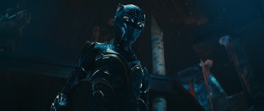 A masked figure stands in a new Black Panther suit in a scene from Black Panther: Wakanda Forever