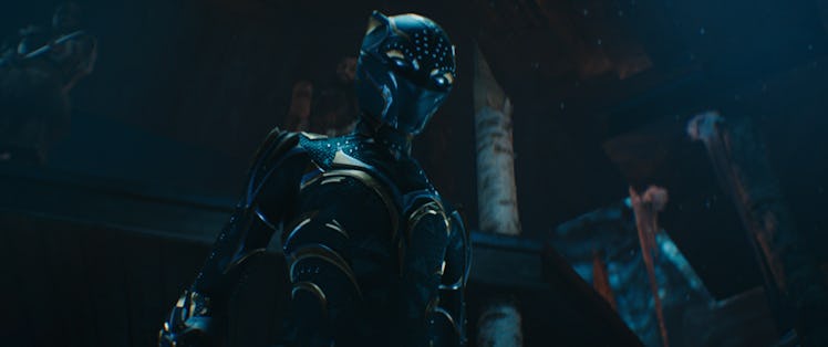 A masked figure stands in a new Black Panther suit in a scene from Black Panther: Wakanda Forever