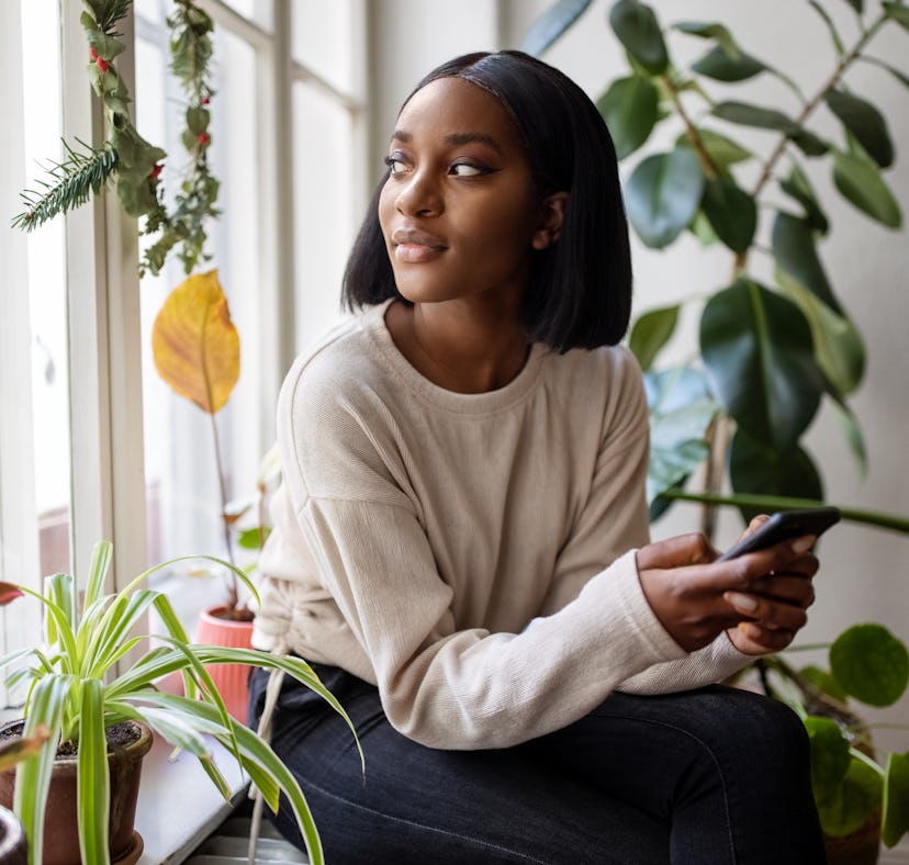 Young woman looking outside on Halloween 2022, which will be low-key for her zodiac sign.